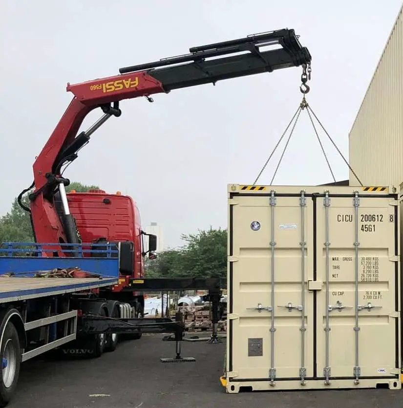 red hiab truck mounted crane picking up a shipping container