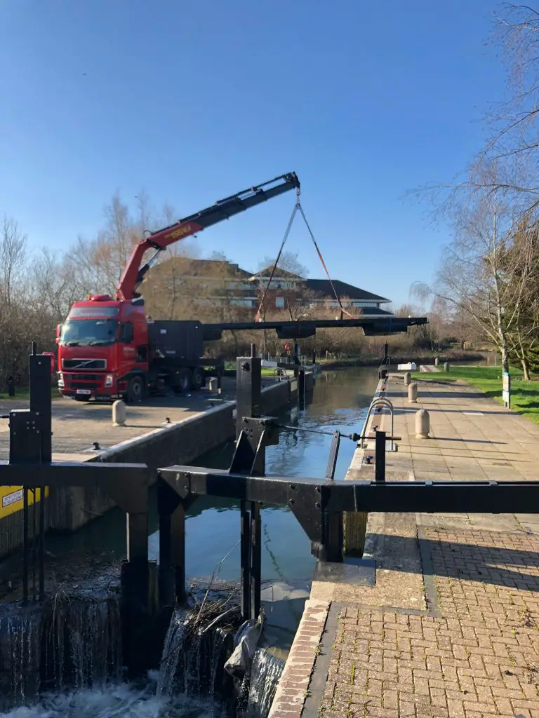 hiab lorry lifting a large beam over a canal